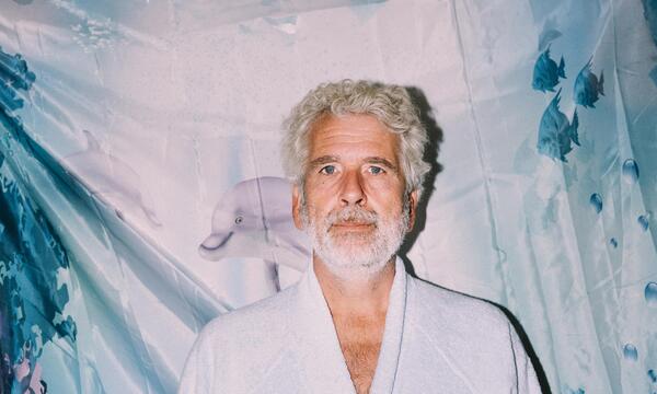 Kabarettist Dirk Stermann im Kuschel-Bademantel mit seinem gestickten Zitat „immer nie am Meer“.