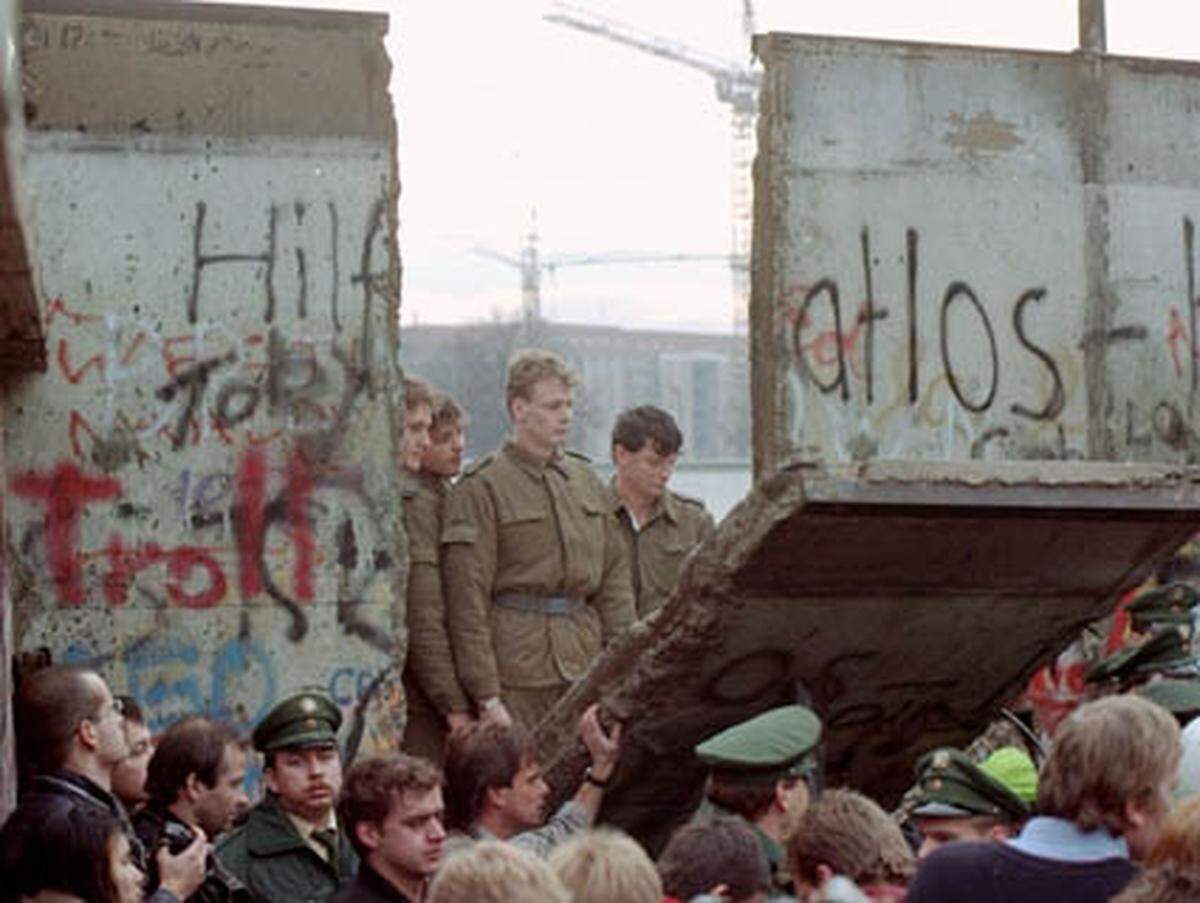 ... in der Nähe des Brandenburger Tors sehen DDR-Grenzer hilflos zu, wie die Menschenmasse ein Mauersegment einreißt.