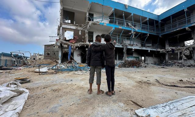 Abed Al-Qara and Muhammad Al-Fajem stehen vor der Ruine ihrer Schule in Khan Yunis, im Süden des Gazastreifens.