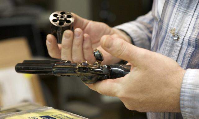 Chris Dogolo inspects a Colt Single Action Army revolver in Guilford