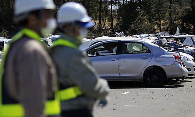 Toyota Motor Corp. workers look at new vehicles damaged by the March 11 tsunami waters in a Toyota pa