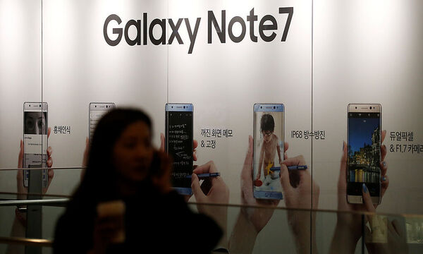 A woman talking on her mobile phone walks past an advertisement promoting Samsung Electronics' Galaxy Note 7 at company's headquarters in Seoul