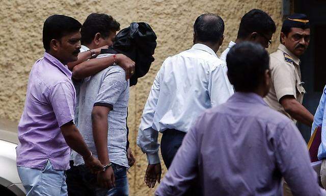 Police officers escort a man, who is accused of raping a photo journalist, at a court in Mumbai