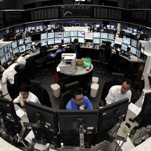 Traders are pictured at their desks in front of the DAX board at the Frankfurt stock exchange