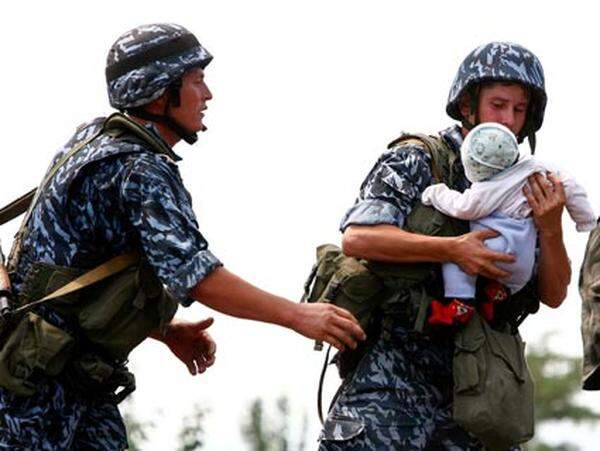 Kirgisische Soldaten helfen einem Kleinkind.