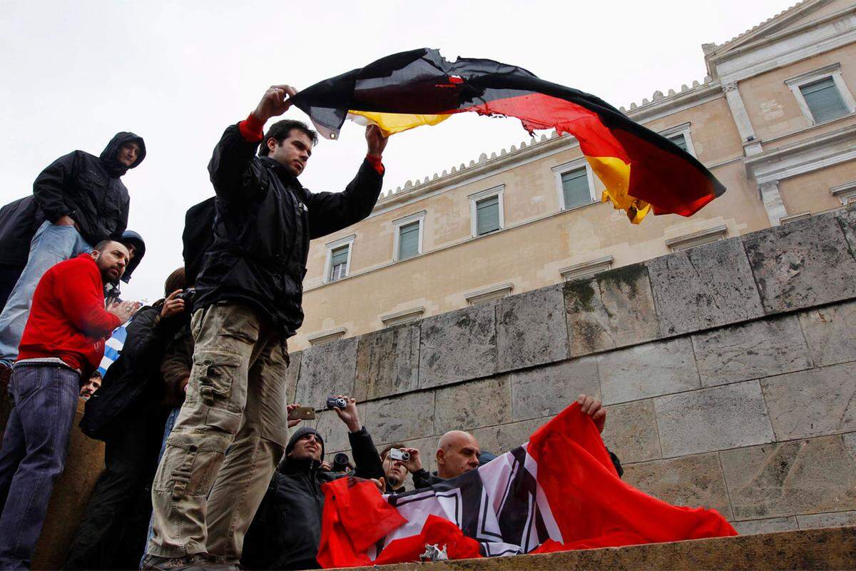 Während die Demonstranten "Räuber, Räuber" in Richtung der im Parlament versammelten Abgeordneten riefen, zog einer von ihnen eine schwarzrotgoldene Flagge hervor und setzte sie in Brand.