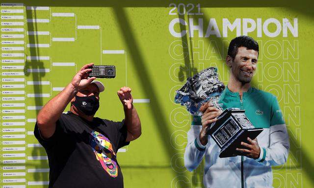 Tennisfan vor Djokovic-Plakat in Melbourne