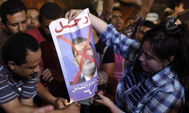 Protesters light a poster of President Mohamed Mursi on fire in Tahrir square, Cairo