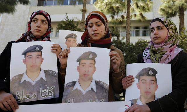 The wife of Islamic State captive Kasaesbeh holds a picture of him as she joins students during a rally calling for his release, in Amman