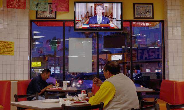 People watch U.S. President Barack Obama´s White House immigration speech on television at a restaurant in Huntington Park