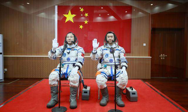 Chinese astronauts Jing Haipeng and Chen Dong wave in front of a Chinese national flag before the launch of  Shenzhou-11 manned spacecraft, in Jiuquan
