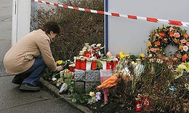 Eine Frau legt am Freitag, 13. Maerz 2009, in Wendlingen vor dem Tatort bei einem Autohaus Blumen nie