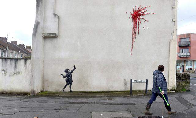 Ein Mädchen mit einer Steinschleuder in der Hand, darüber ein riesiger roter Klecks - von Banksy?