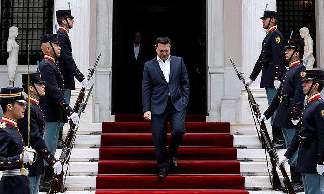 Greek PM Tsipras walks down the stairs of the Maximos Mansion next to an honorary guard as he arrives to welcome Portugal's PM Costa in Athens