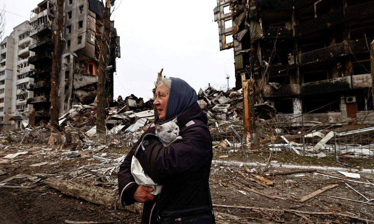 5. April. Eine Frau trägt ihre Katze, während sie an Gebäuden vorbeigeht, die durch den russischen Beschuss während des russischen Einmarsches in die Ukraine in Borodjanka in der Region Kiew, Ukraine, zerstört wurden.