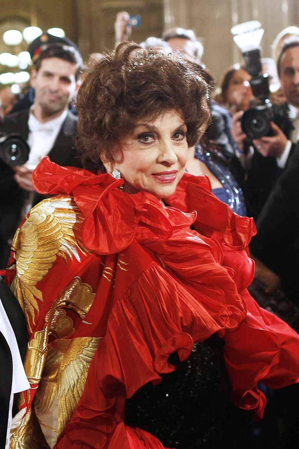 Gina Lollobrigida trug über ihrer schwarzglitzernden Robe einen knallroten, gerüschten Seidenumhang mit aufgesticktem Drachen.