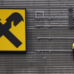 Workers are suspended as they assemble letters of the Raiffeisen Polbank's bank logo on their new building in Warsaw