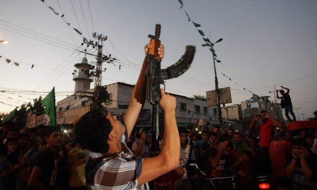 A Palestinian gunman fires in the air while celebrating after a deal had been reached between Hamas