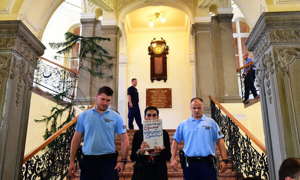 Der Hauptverdächtige und mutmaßliche Boss der Schlepperbande, der Afghane Samsooryamal L., bei der Eröffnung des Prozesses am Mittwoch. Dabei trat er mit einer Tafel auf, auf der stand, er sei „Muslim, kein Mörder“.