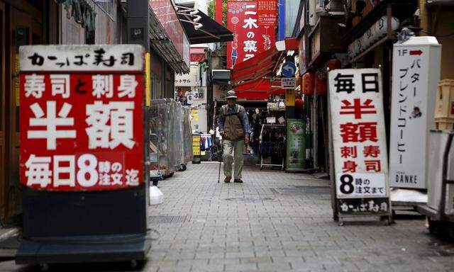 A man walks between discount advertisements of restaurants at a shopping district in Tokyo