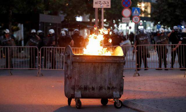 Eine Mülltonne brennt vor einer Sperre der Bereitschaftspolizei nach einer Protestkundgebung anlässlich der inoffiziellen Feier des Tages der Staatlichkeit in Niksic, Montenegro, am 13. Juli 2022.