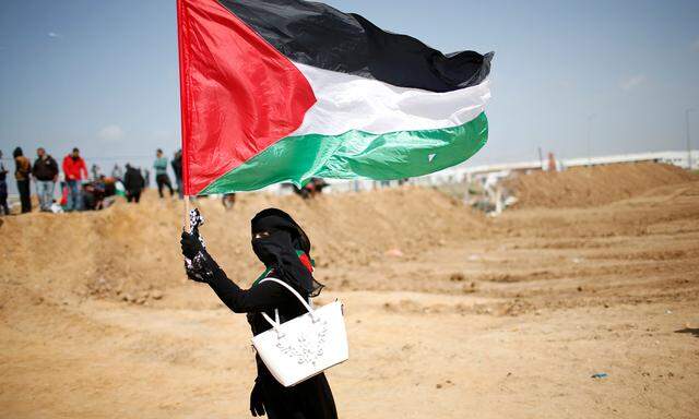 A woman waves a Palestinian flag ahead of a protest in a tent city along Israel border with Gaza, demanding to return to their home land, east of Gaza City