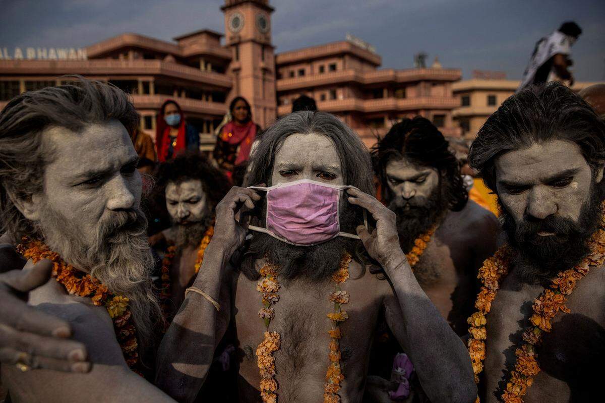 Ein indischer Naga Sadhu (zu deutsch ‚Guter oder auch: Heiliger Mann') setzt die Maske auf, bevor er bei einer Prozession in den Ganges steigt.