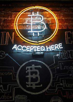 A neon logo of virtual cryptocurrency Bitcoin is seen at the Bitcoin Embassy bar in this illustration