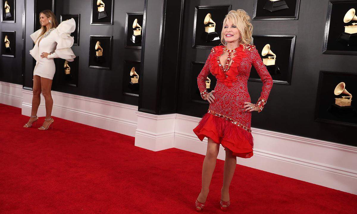 Country-Sängerin Dolly Parton hat es gern verspielt, knallig, glänzend und körperbetont. Eine Dame, die es mit ihren Red-Carpet-Outfits ebenfalls gerne übertreibt, kündigt sich bereits im Hintergrund an.