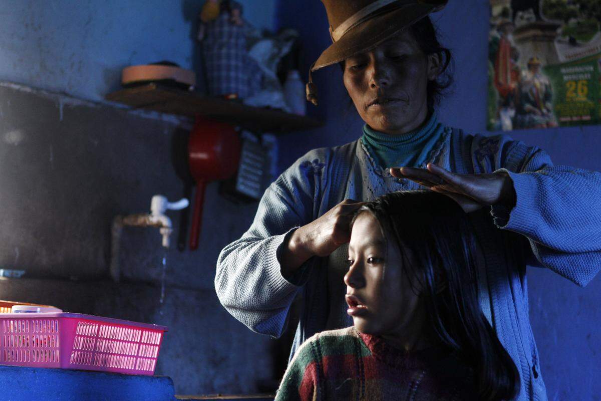 Octavia Ccahuata kämmt die Haare ihrer Tochter in der Küche ihreres Hauses. Es ist Teil eines Ökölogieprojektes in den Anden, bei dem Solarkraft dazu verwendet wird, das Wasser zu erwärmen und auch in den kalten Wintern in der Region energiesparend zu heizen. Aufnahme vom 9. März 2012.
