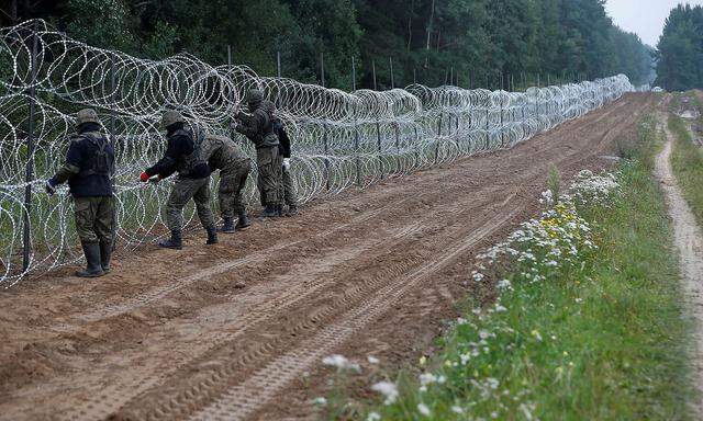 FILE PHOTO: Polish soldiers build a fence on the border between Poland and Belarus near the village of Nomiki