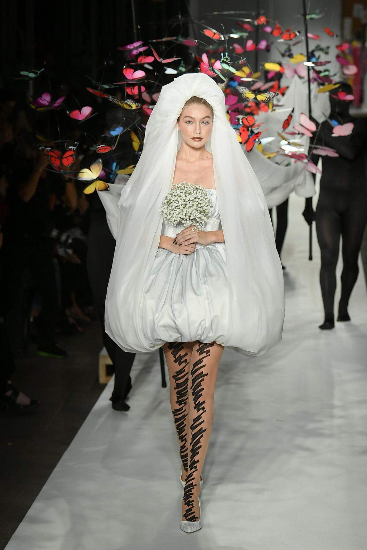 Powerdressing, subtile Silhouetten und kunstvolle Prints. So zeigt sich die Mode bei der Mailänder Modewoche. Bei Moschino schritt Model Gigi Hadid als etwas andere Braut über den Catwalk.