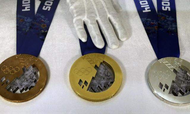 Employee arranges medals for the 2014 Winter Olympic Games during a presentation for the public at a jewellery shop in St. Petersburg