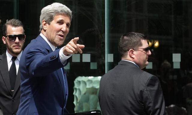 U.S. Secretary of State Kerry points to journalists as he walks to a meeting at a hotel in Vienna