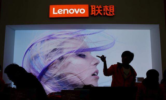 FILE PHOTO: An employee gestures next to a Lenovo logo at Lenovo Tech World in Beijing