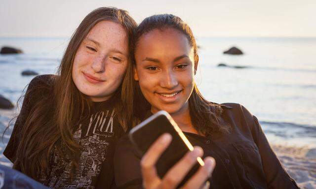 Germany Ruegen Two young female friends with smartphone at the beach model released Symbolfoto PUB