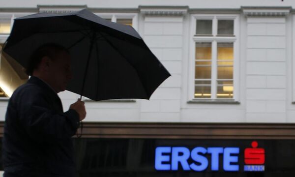 A man with an umbrella passes the entrance of the headquarters of Austrian Erste Group Bank  in Vienna