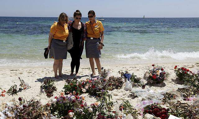 Hotel workers observe a minute's silence in memory of those killed in a recent attack by an Islamist gunman, at a beach in Sousse