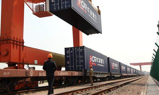Workers are seen next to a train loaded with China Railway Express containers at the railway port in Yiwu