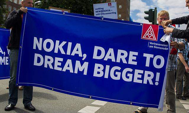 Nokia employees unfold banners during protest denouncing plans to cut jobs at Nokia´s Berlin branch in Berlin