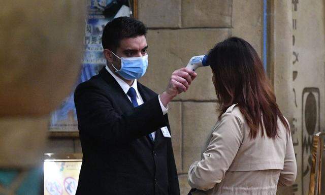 Der Mitarbeiter eines Luxuxhotels in Macau prüft die Temperatur einer Besucherin mittels Fieberthermometer. Eine der Vorsichtsmaßnahmen, die sich in nächster Zeit häufen werden.