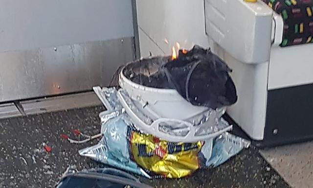 Aufnahme des noch leicht brennenden Sprengsatzes in einem Kübel kurz nach der Detonation in der U-Bahn-Garnitur