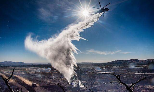 Verbrannte Erde: Ein Löschhelikopter verteilt in der Nähe von San Bernardino Wasser auf ein schwelendes Glutnest.
