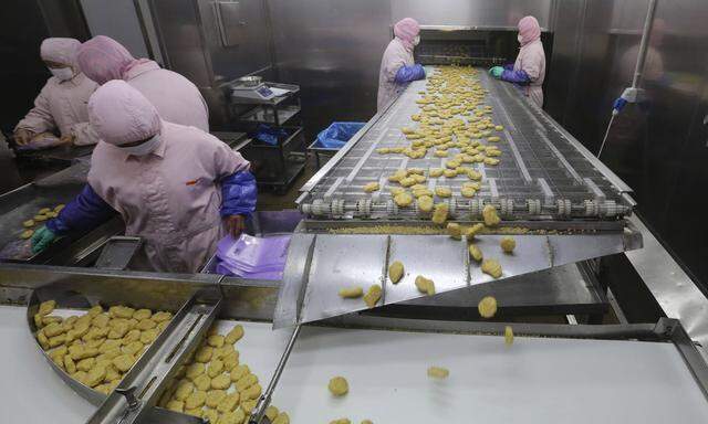 Employees work at a production line prior to a seizure at the Husi Food factory in Shanghai