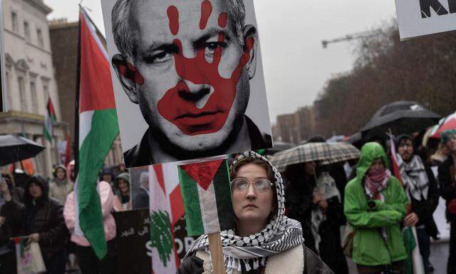 DUBLIN, IRELAND - FEBRUARY 17: A female protester raise a placard with a depiction of a red hand on the face of Benjamin Netanyahu during a protest held by the Ireland-Palestine Solidarity Campaign on February 17, 2024 in Dublin, Ireland. (Photo by Natalia Campos/Getty Images)