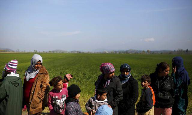 Migrants and refugees queue to receive food at a makeshift camp at the Greek-Macedonian border near the village of Idomeni