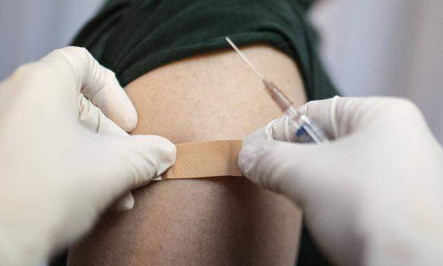 Thema: Impfung. Arzt klebt ein Pflaster auf die Einstichstelle Bonn Deutschland *** Topic Vaccination Doctor sticks a p