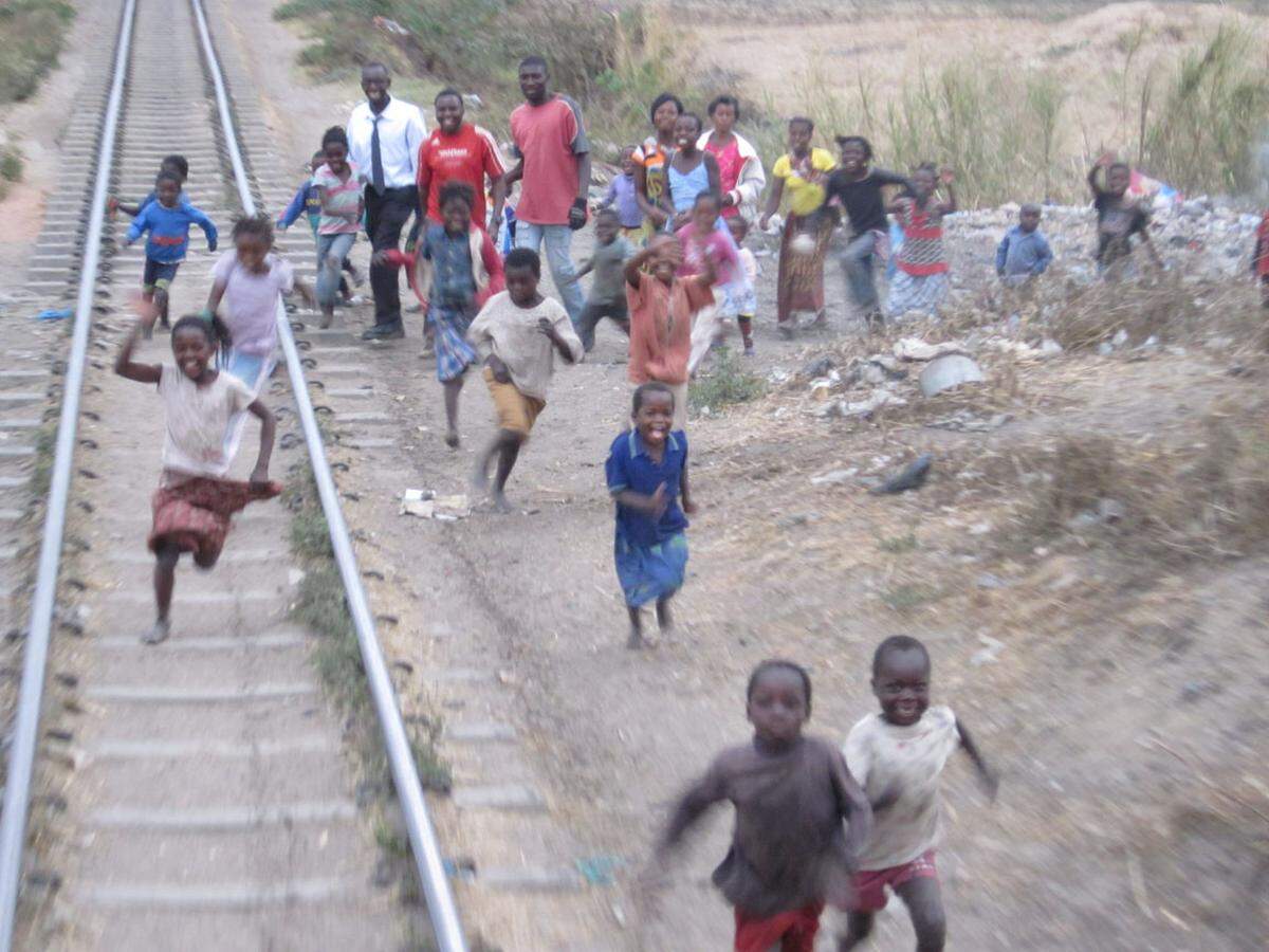 Ausfahrt Lusaka, hunderte Kinder rennen dem letzten Waggon des Luxuszugs hinterher, auf dem sich die Aussichtsplattform befindet.