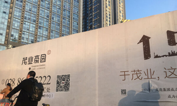 Man cycles past a residential property under construction in Chengdu