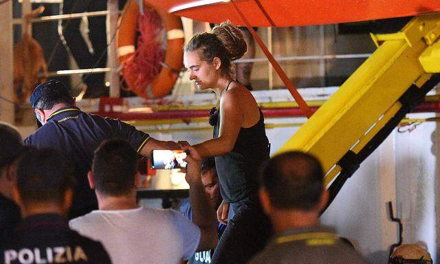 Carola Rackete, the 31-year-old Sea-Watch 3 captain, is escorted off the ship by police and taken away for questioning, in Lampedusa